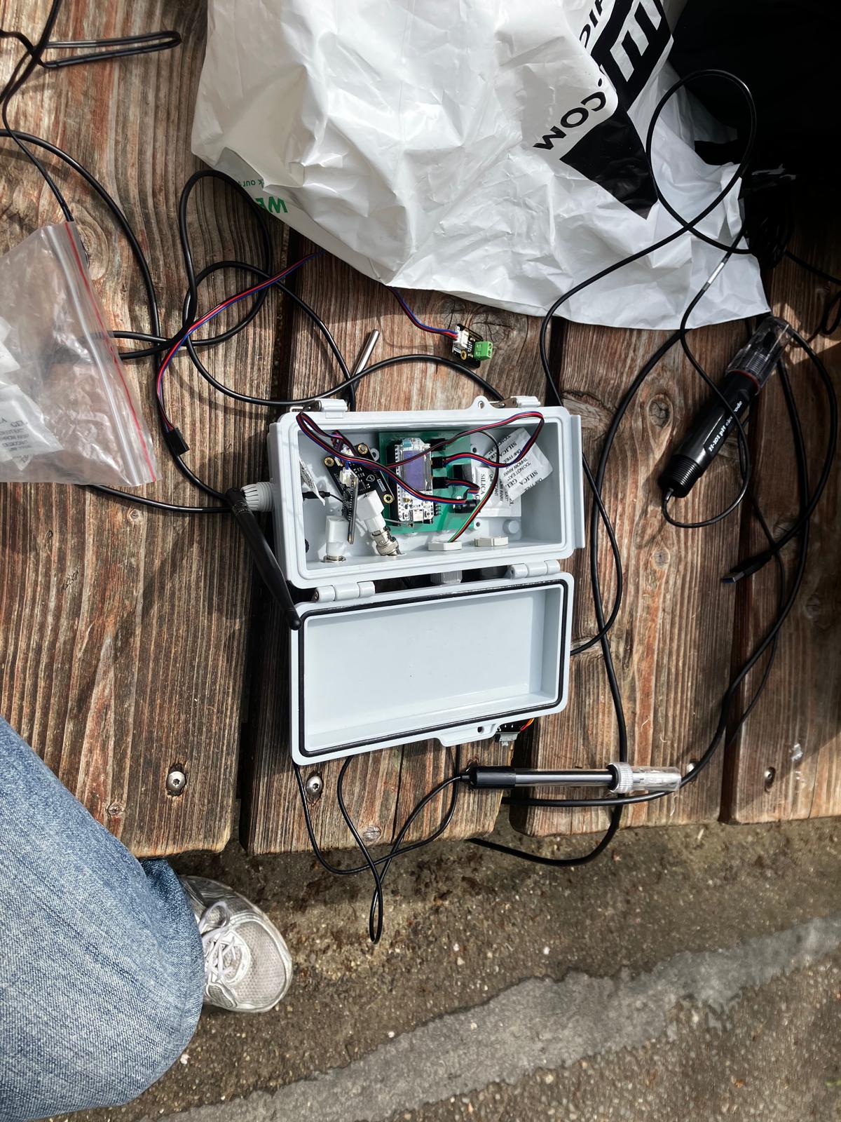 afbeelding van een technisch apparaat op een houten vlonder met allerlei electrische draden