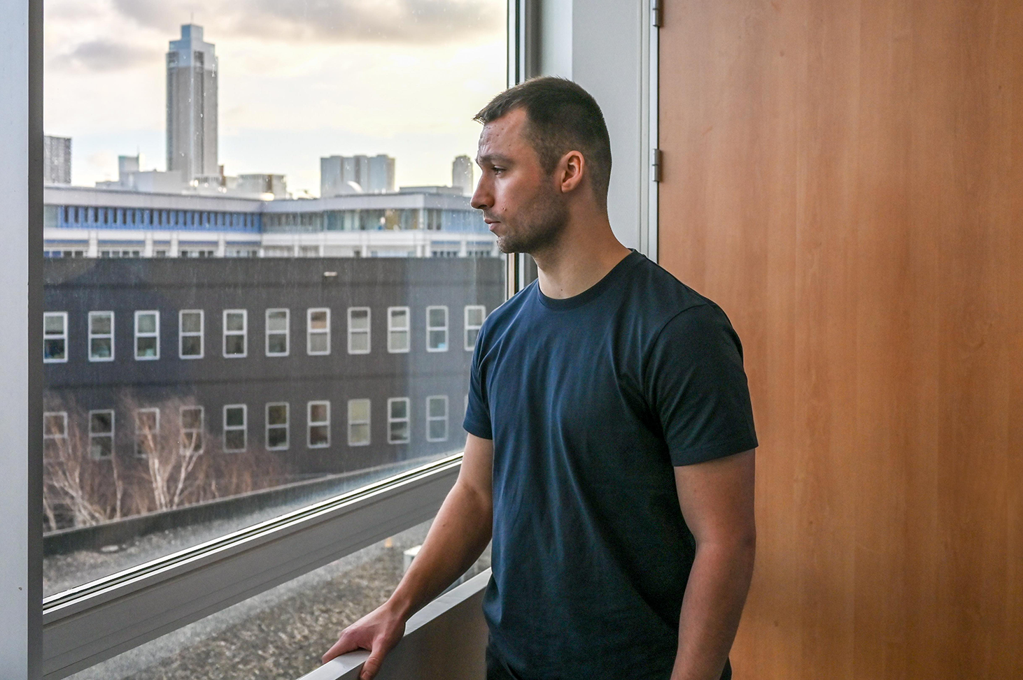 Student Leon kijkt door het raam van Museumpark waar hij studeerde naar de skyline van Rotterdam