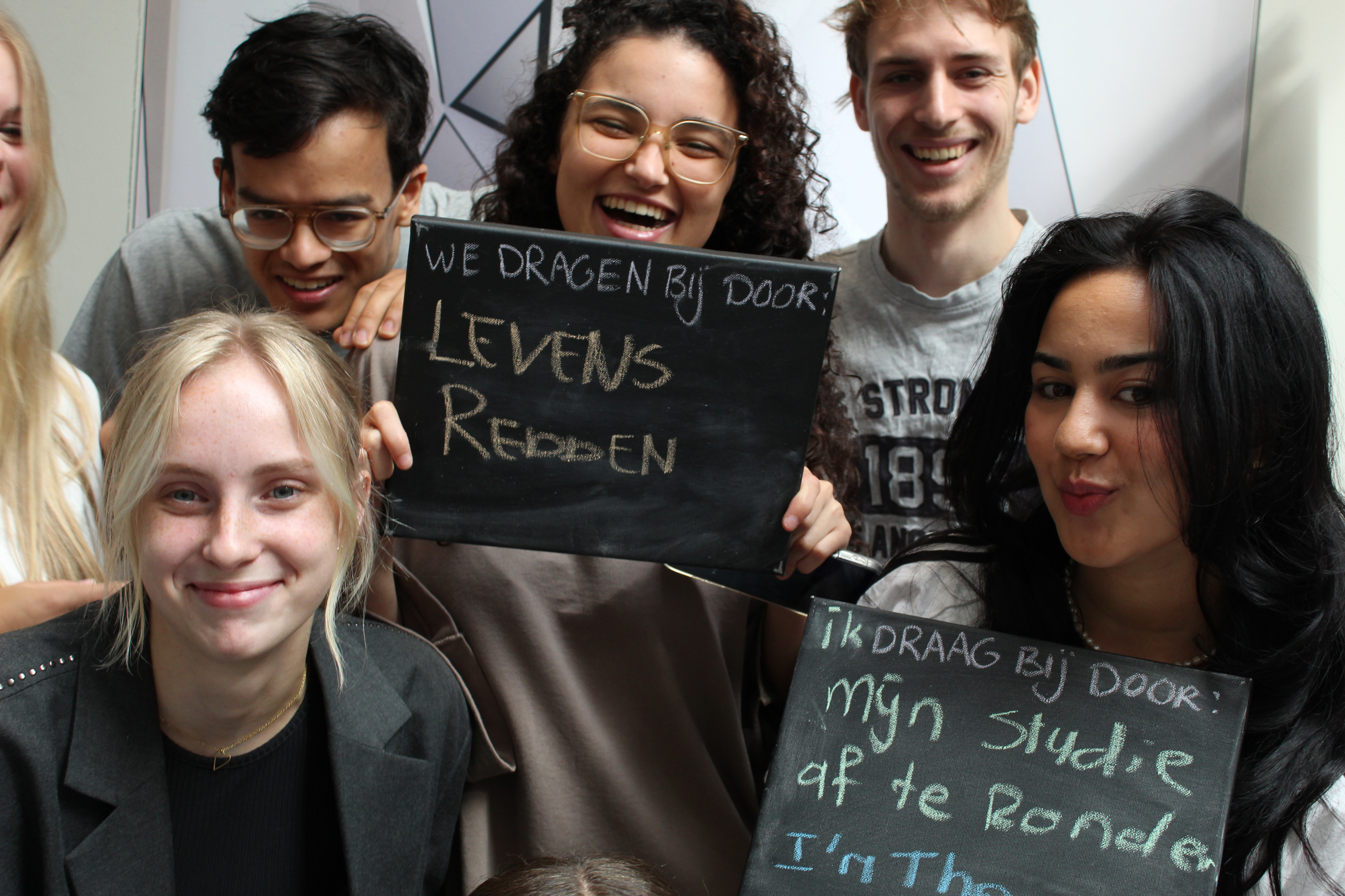 Lachende studenten houden een borst vast met daarop hun bijdrage aan een vitale gemeenschap