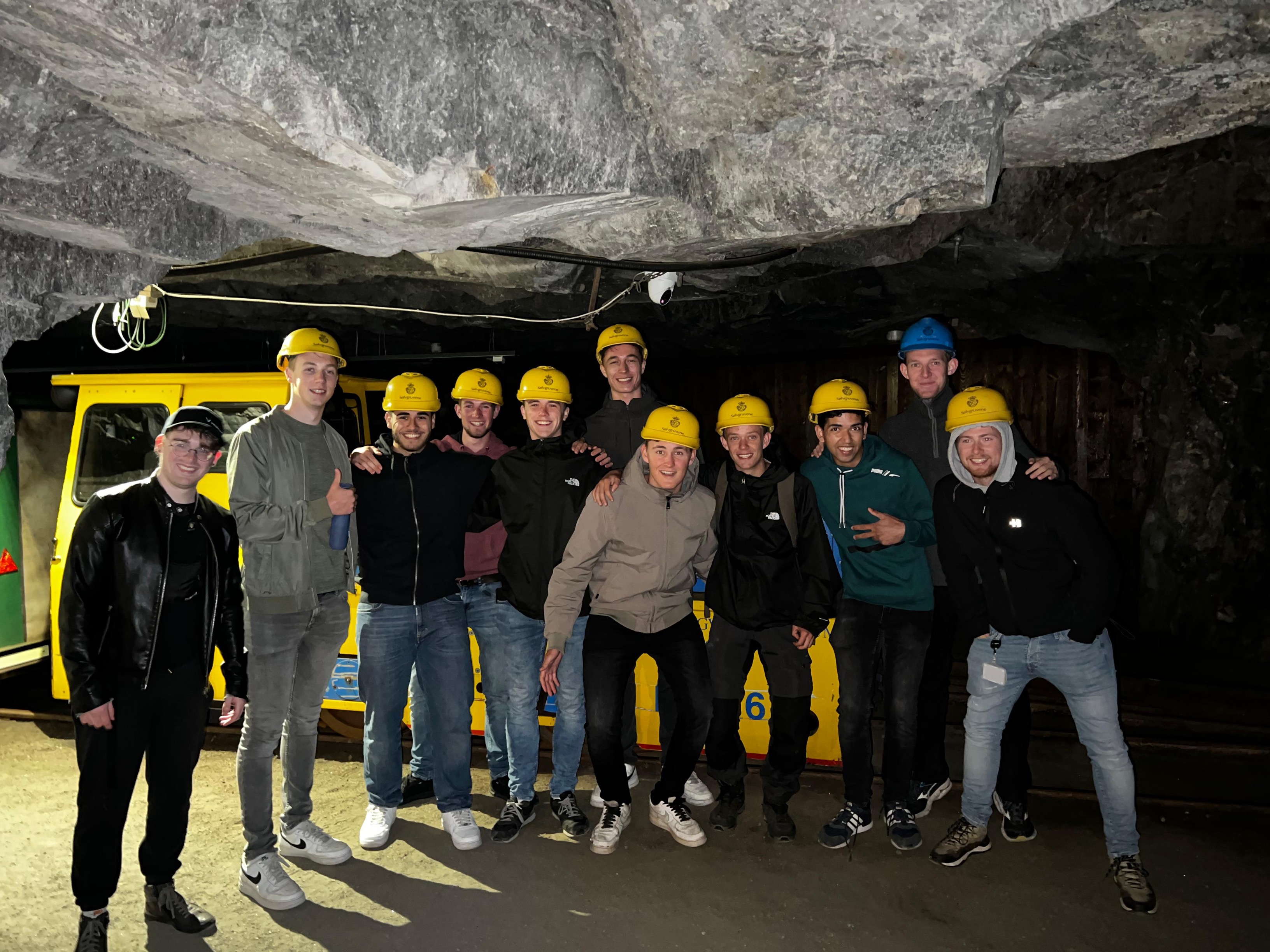 De studenten poseren met helm in een grot
